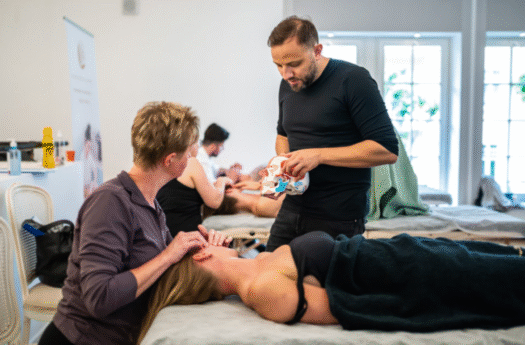 doświadczony fizjoterapeuta pokazuje terapeutce techniki masażu twarzy podczas szkolenia masażu Kobido
