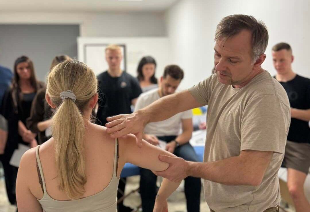 Doświadczony fizjoterapeuta Bartosz Rutowicz wykonuje badanie barku